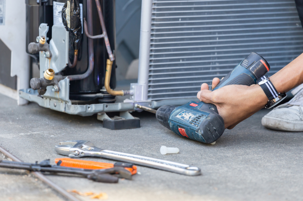 A technician performs maintenance on an outside AC unit.