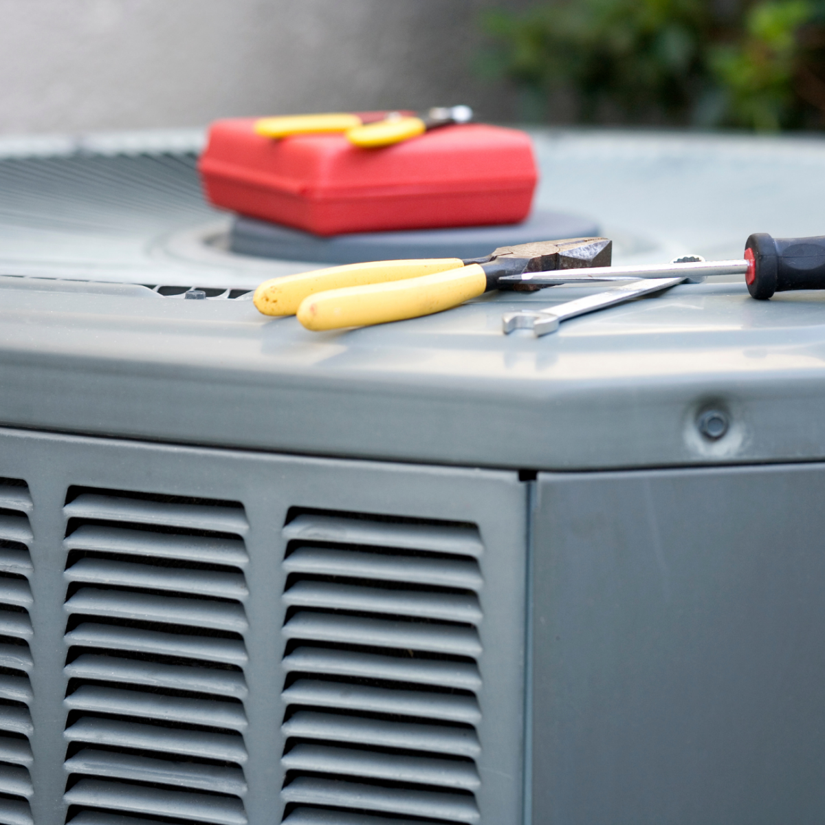 An outside AC unit with tools sitting on the top.