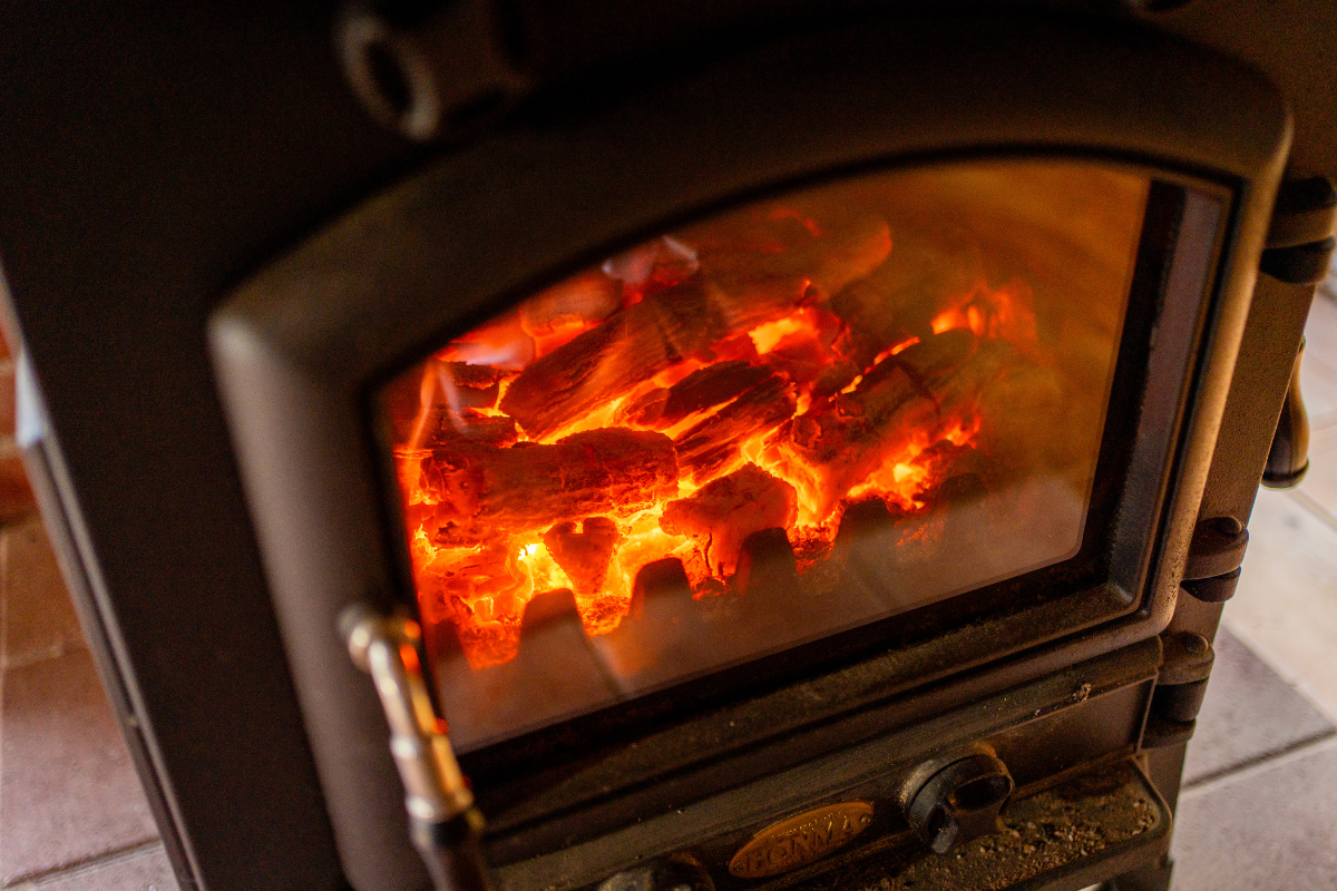 Glowing embers of burning logs in a wood stove give a cozy heat.