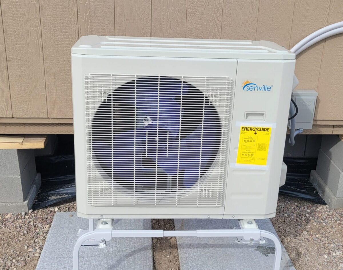 Ductless mini split outdoor unit on a stand beside a small Montana home.
